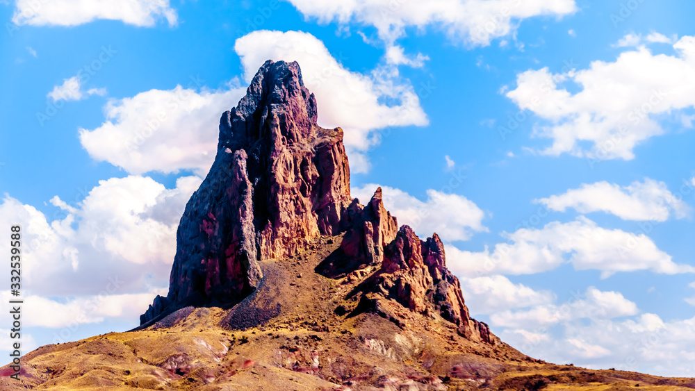 The rugged peaks of El Capitan and Agathla Peak towering over the desert landscape south of Monument Valley along Highway US Route 163 in northern Arizona, United States