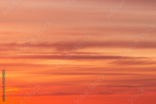 Bright soft sunrise, sunset orange yellow red sky with clouds background texture 