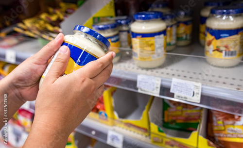 Woman hand holding Mayonnaise bottle and Empty shelves of oil in supermarket Panic buyer for hoarding food