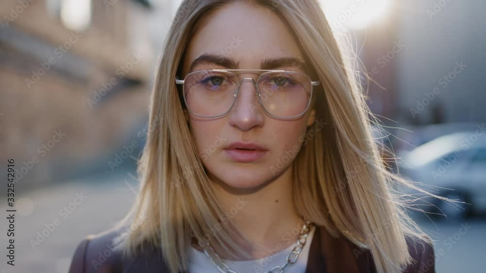 Close up portrait of beautiful european blonde woman in glasses looking to the camera spring sunny day sunlight outdoor slow motion Close up portrait of beautiful european blonde woman in glasses looking to the camera spring sunny day sunlight outdoor slow motion