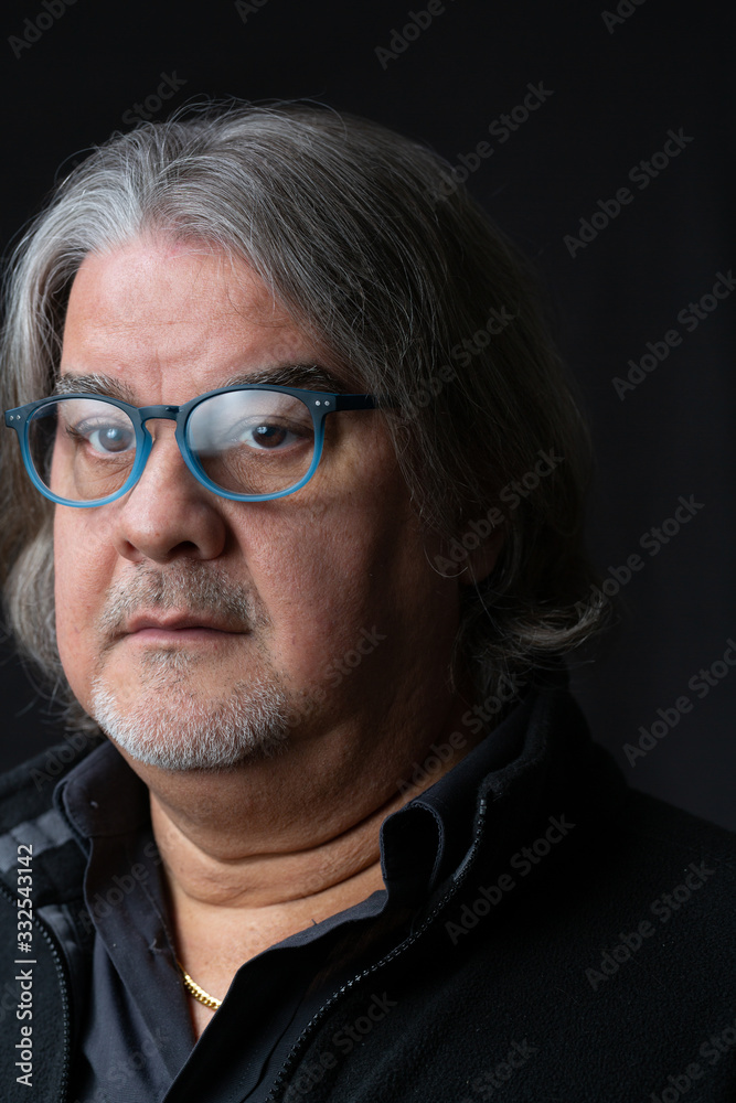 Studio head shot of man. He is serious, wearing prescription glasses and looking to the camera.. Studio head shot of man. He is serious, wearing prescription glasses and looking to the camera..