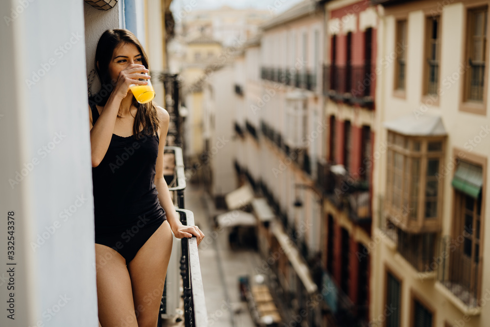 Young european woman spending free time home.Self care,staying home.Enjoying view on the balcony.Relaxing at home.Hotel room balcony view,vacation in Europe.Drinking orange juice in the morning