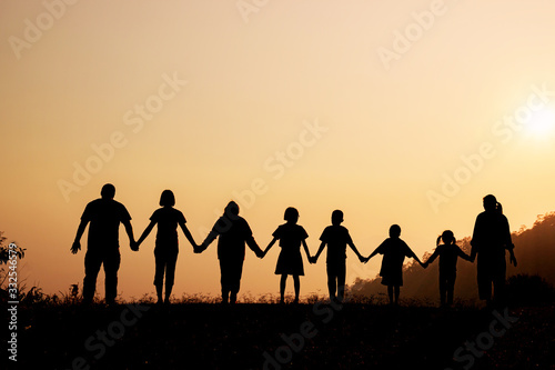 Silhouette of happy family standing on the mountain at the sunset time.