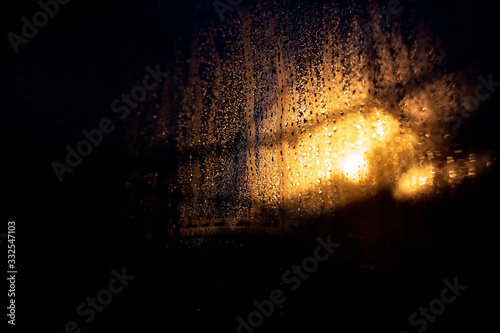 Rain drops on the glass on a background of a night blurred light