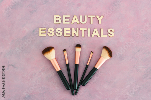 beauty essentials text with make-up brush set on pink background