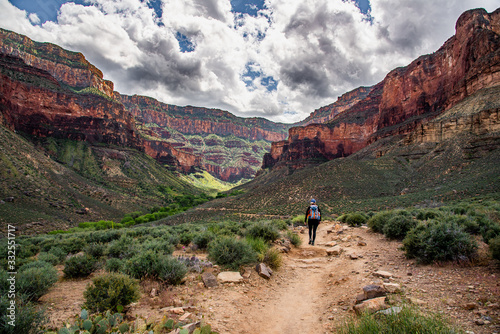 Woman hiking in the Grand Canyon in Arizona during summer time with amazing Colorado River in background below. Summer time, road trip travel area in United States of America. 