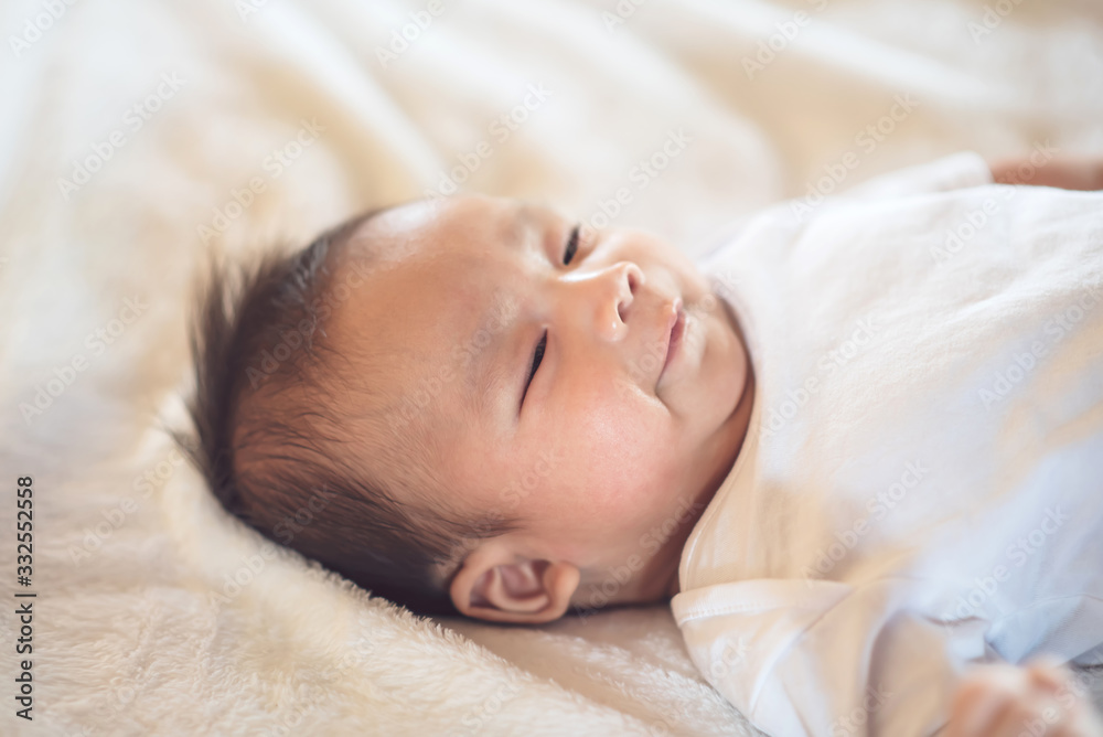 Newborn baby lying on a soft white mattress, smiling happily. Newborn baby lying on a soft white mattress, smiling happily.