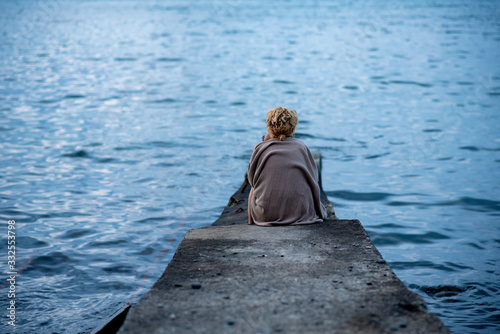 Back view of a blonde woman in front of the sea view.