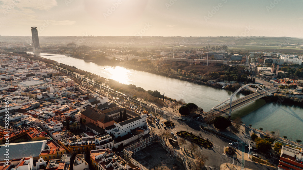 Fototapeta premium Aerial view of Barqueta Bridge over Guadalquivir River in Seville, Andalusia, Spain. Sunset in Seville,city center and Sevilla tower.Entrance to the city, transportation stations.Traffic in Seville.