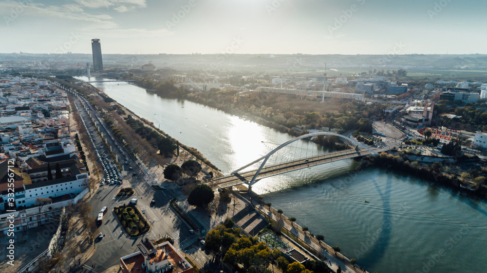 Obraz premium Aerial view of Barqueta Bridge over Guadalquivir River in Seville, Andalusia, Spain. Sunset in Seville,city center and Sevilla tower.Entrance to the city, transportation stations.Traffic in Seville.