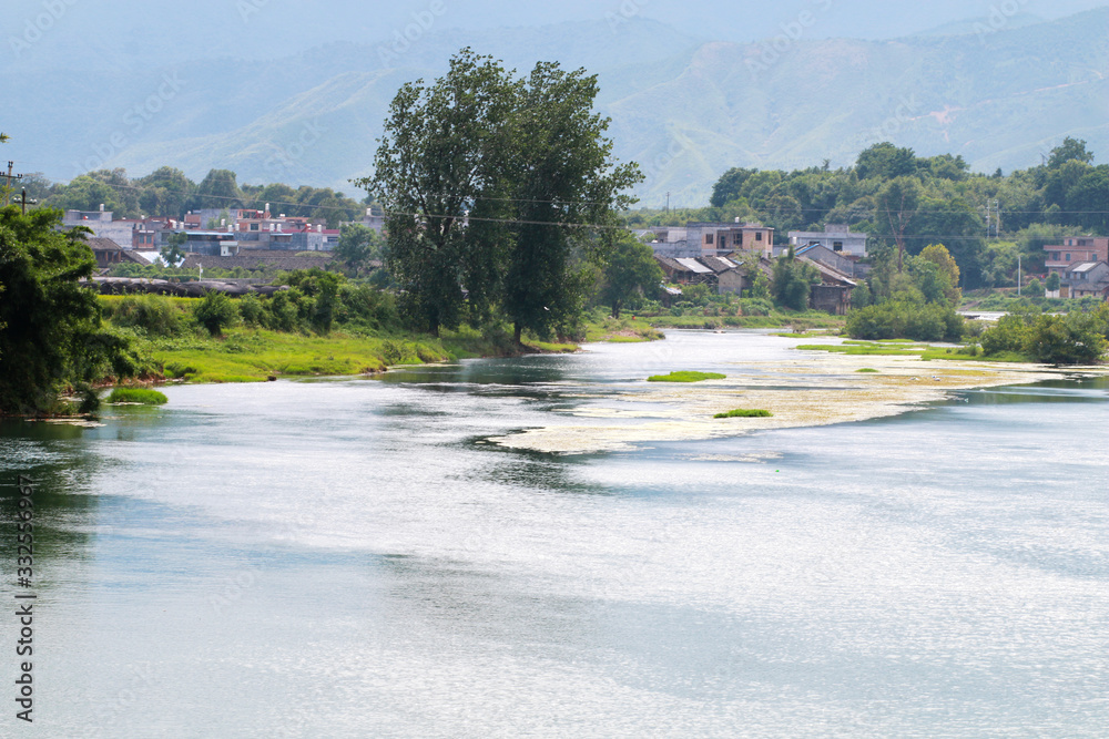 A village near a hill and a river A village near a hill and a river