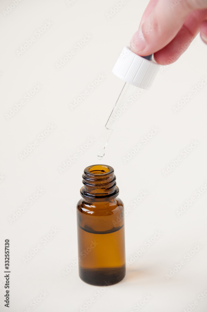 Hand holding a pipette over a dark glass bottle , nose drops, eye drops Hand holding a pipette over a dark glass bottle , nose drops, eye drops