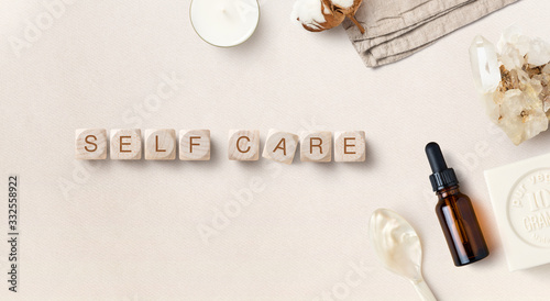 self care during quarantine / self-isolation / pandemic- conceptual image with dropper bottle, soap and wooden dices reading "self care", flat lay / top view