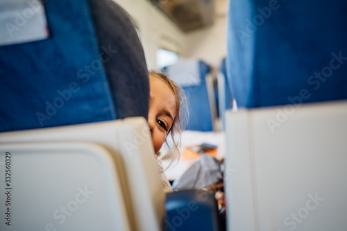 Child peeking between seats.Child sitting in front seat.Children on plane/bus/train rides.Children in transportation.Anoying kid.Airplane child passenger,traveling with kids. photo