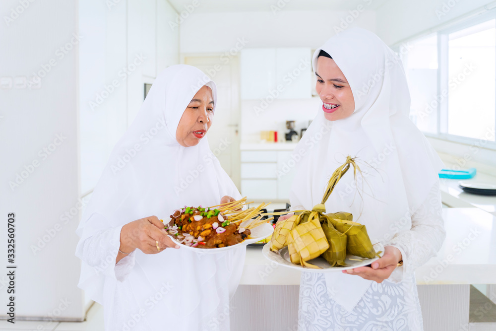 Mother and young woman holding traditional food Mother and young woman holding traditional food