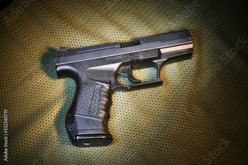 Pistola de airsoft em cima de tecido verde militar. Brinquedo simulacro de arma de fogo photo