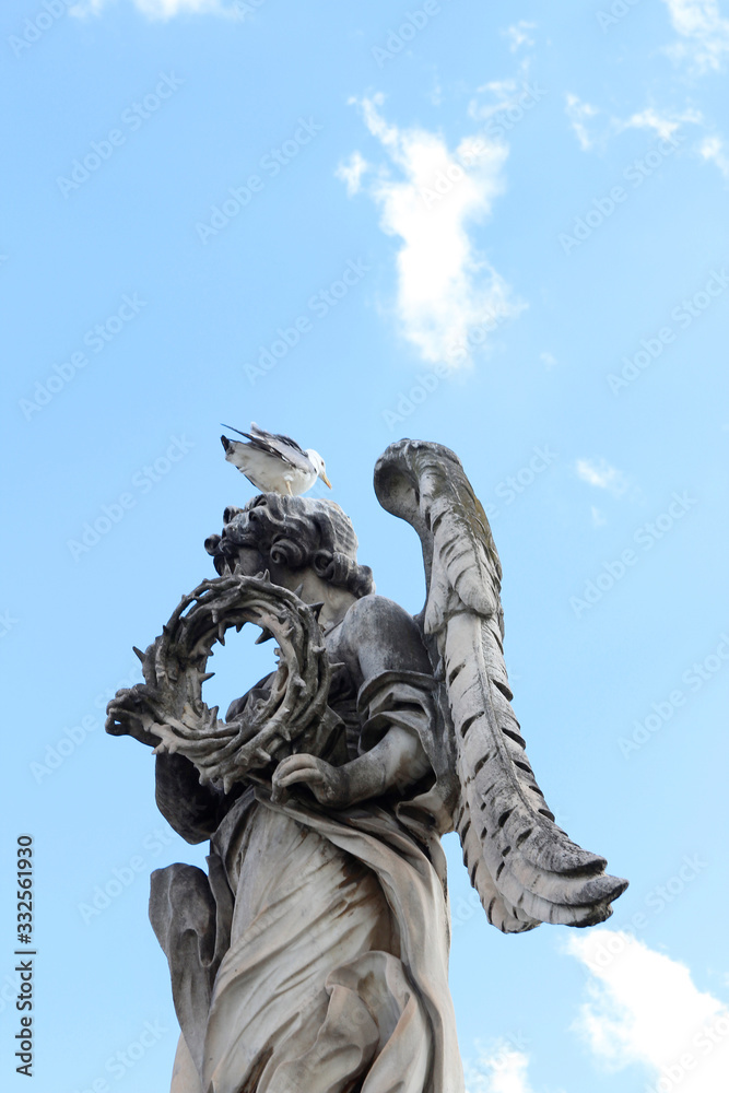 Fototapeta premium Angel Carrying the Crown of Thorns by Gian Lorenzo Bernini and a seagull stand on the top statue at Castel Sant'Angelo, Rome, Italy