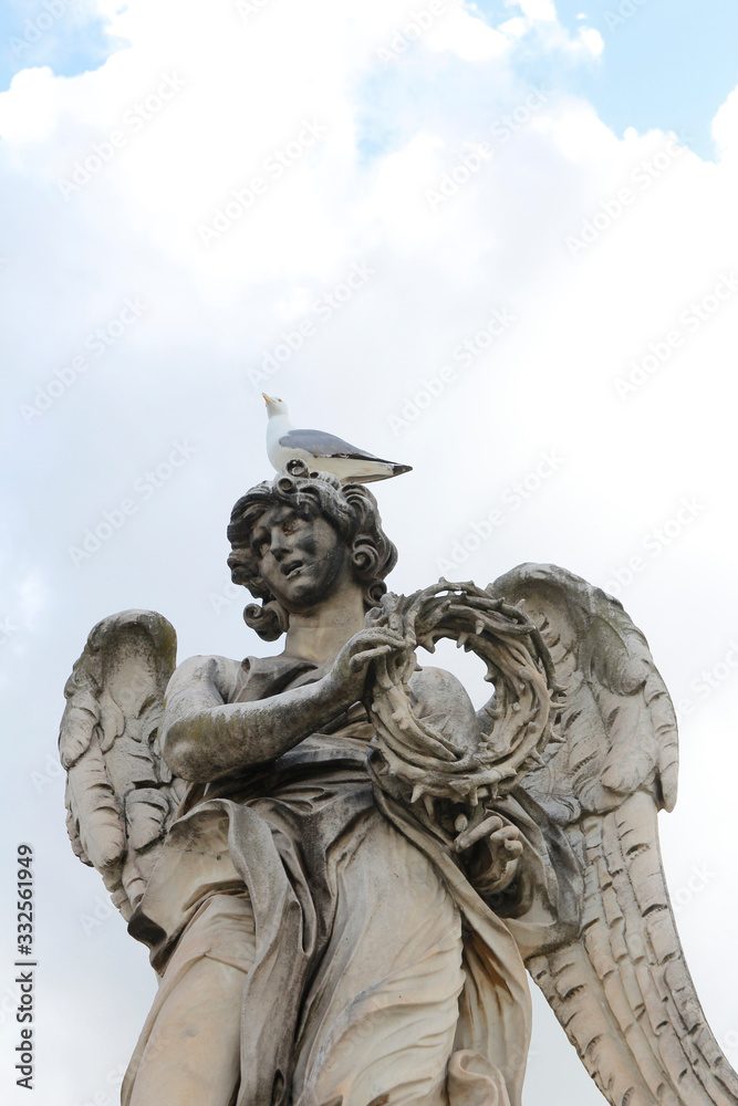 Angel Carrying the Crown of Thorns by Gian Lorenzo Bernini and a seagull stand on the top statue at Castel Sant'Angelo, Rome, Italy