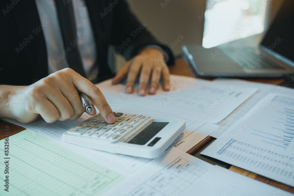 Businessmen are calculating the cost of the company's sales and analyzing the graph in the office. Businessmen are calculating the cost of the company's sales and analyzing the graph in the office.