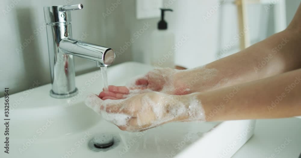 CINEMAGRAPH - seamless loop. Washing hands woman rinsing soap with running water at sink, Coronavirus prevention hand hygiene. Corona Virus pandemic protection cleaning hands.