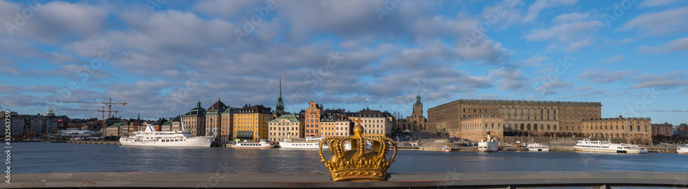 Obraz premium View over the old town district Gamla Stan from the island Skeppsholmen in a sunny spring morning with boats and harbor piers.