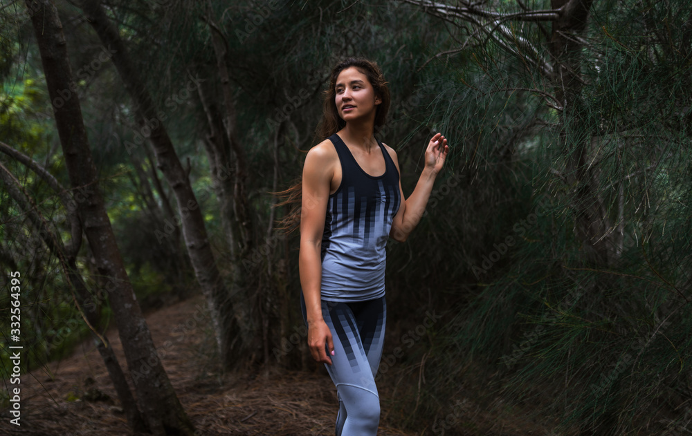 Fit girl enjoys walking through the pine trees forest at sunset hike Fit girl enjoys walking through the pine trees forest at sunset hike