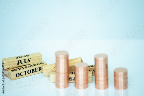 Wallpaper Mural Miniature people: Wooden month and stack of coins with copy space for text using as background saving, investment, money, financial, business analytics concept. Torontodigital.ca