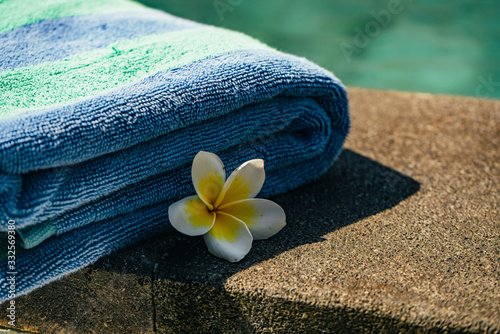 Blue towel and franjipani flower near swimming pool photo