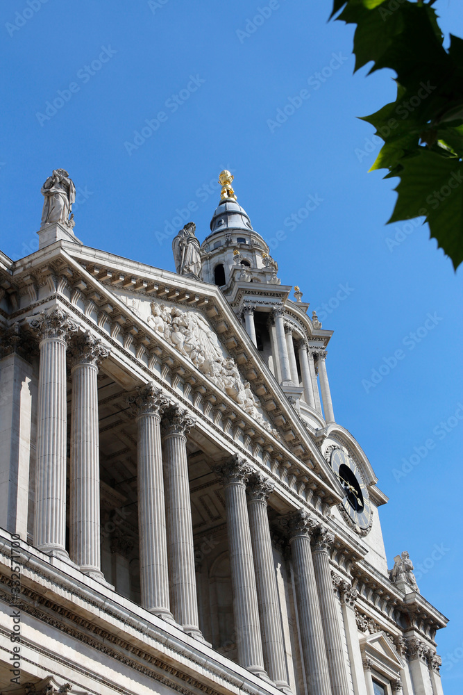 West front of St Paul's Cathedral as clear background and green leaves as blur foreground , London, UK
