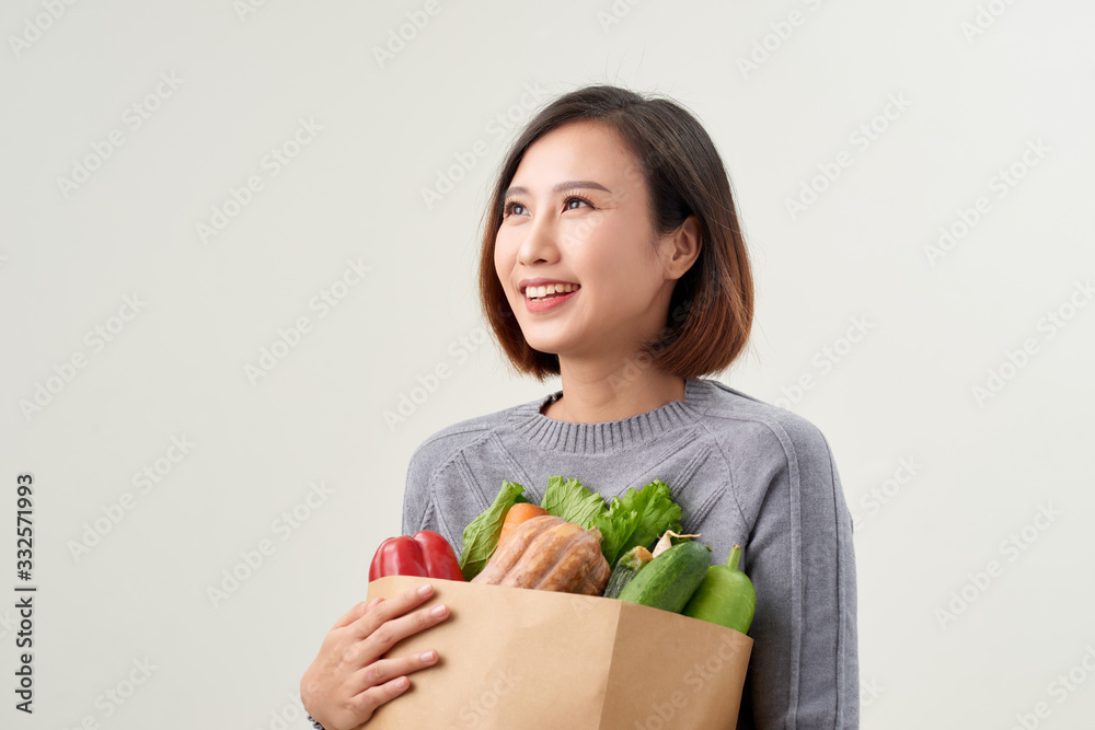 Cheerful woman holding a shopping bag full of groceries Cheerful woman holding a shopping bag full of groceries