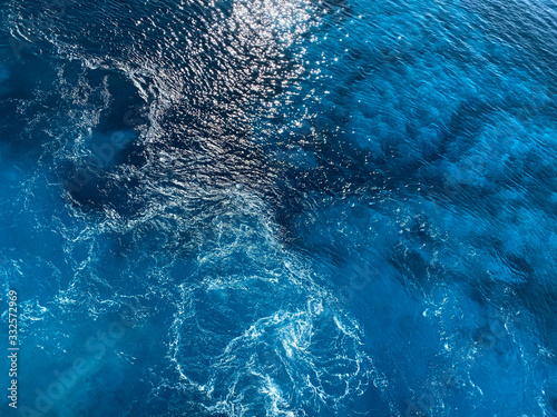 Natural blue background. Blue surface of sea water with wave. Texture of blue water. Abstract textured backdrop. Horizontal, blur, cropped shot, free space for text. Concept of natural beauty