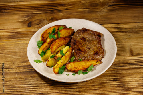 Fried beef steak with potato wedges on wooden table