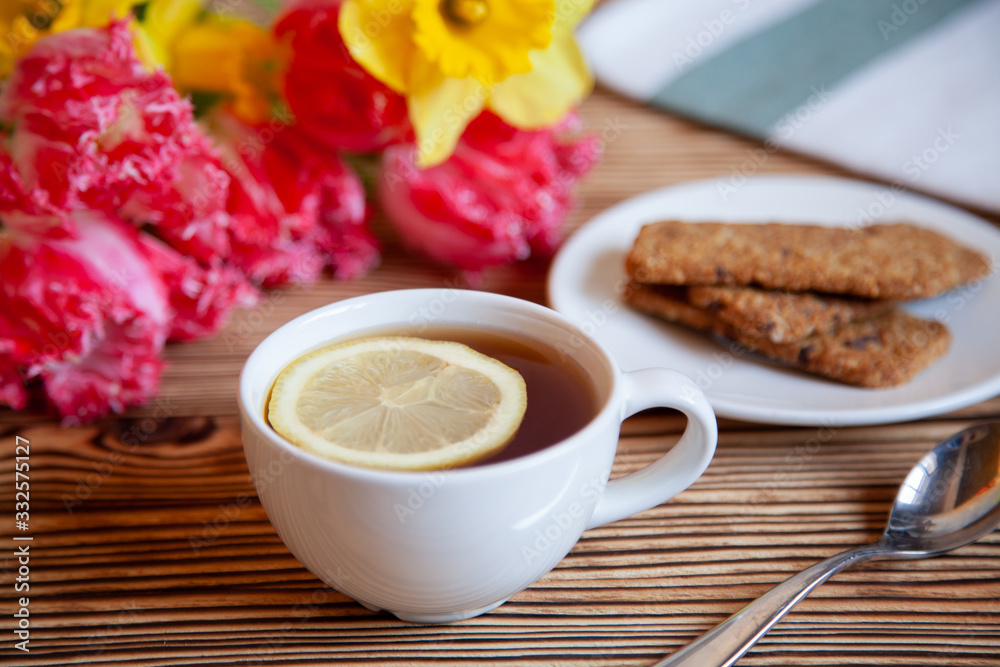 Cap of tea with lemon and flowers and cookies on the wooden table. Cap of tea with lemon and flowers and cookies on the wooden table.