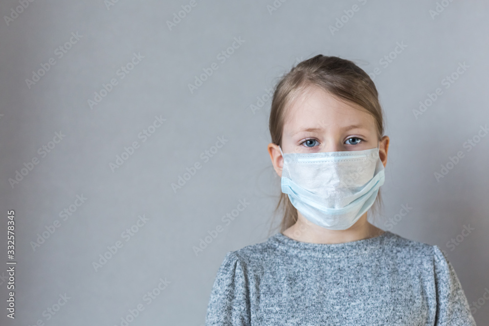 Concept of coronavirus and air pollution. A little European girl wears a medical mask for protection to stop an outbreak of the corona virus.symptoms of an epidemic virus. copy space Concept of coronavirus and air pollution. A little European girl wears a medical mask for protection to stop an outbreak of the corona virus.symptoms of an epidemic virus. copy space