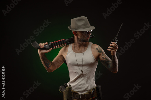 athletic guy with a tattoo poses with a shotgun