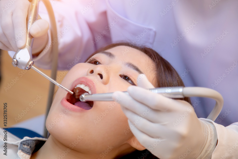 Young man dentist who treats teeth of young woman patient.