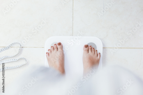 feet standing on electronic scales for weight control. Measurement instrument in kilogram for a diet control.