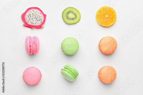 Tasty macarons with fruits on white background