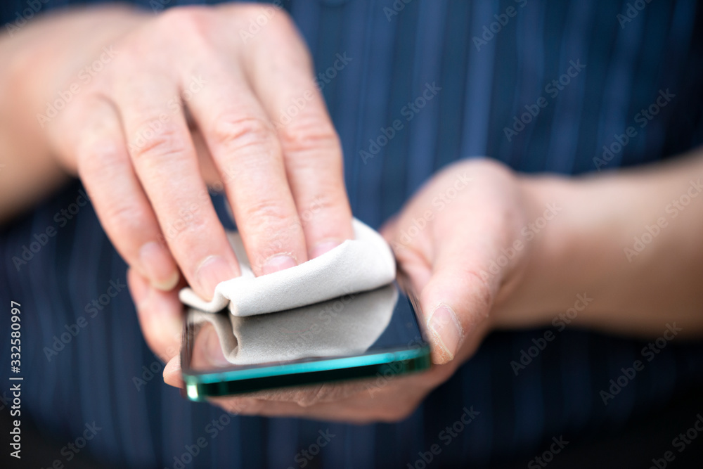 An elderly man is disinfecting a mobile phone