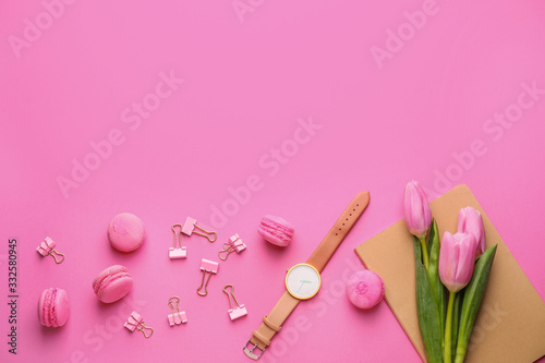 Stationery and clock with tasty macarons on color background