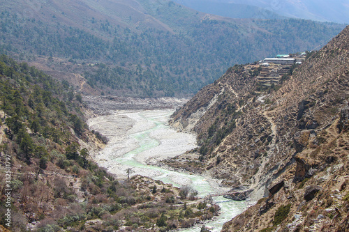Imja Khola river flows in mountain valley in Himalayas. Panboche village is located on cliff near footpath leading to Everest base camp. Beautiful landscape. Theme of trekking in Nepal.