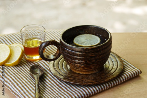 Wooden cup of herbal tea on wooden table with lemon and honey , selective focus.