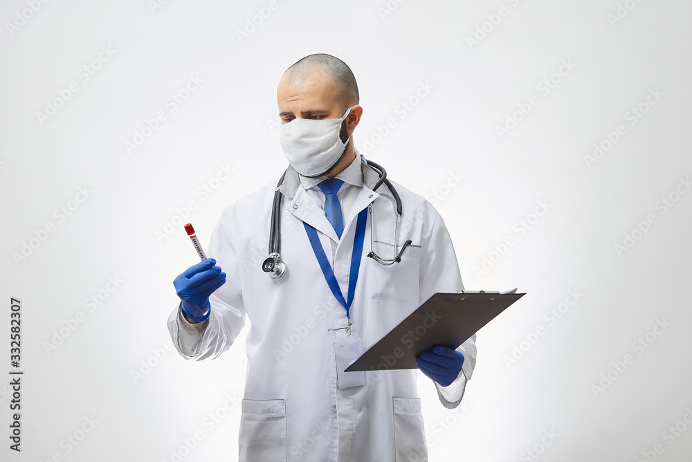 A doctor in a protective face mask thinking about a coronavirus blood test in his hand. A portrait of an infectious disease physician holding a positive COVID-19 blood sample and a clipboard. A doctor in a protective face mask thinking about a coronavirus blood test in his hand. A portrait of an infectious disease physician holding a positive COVID-19 blood sample and a clipboard.