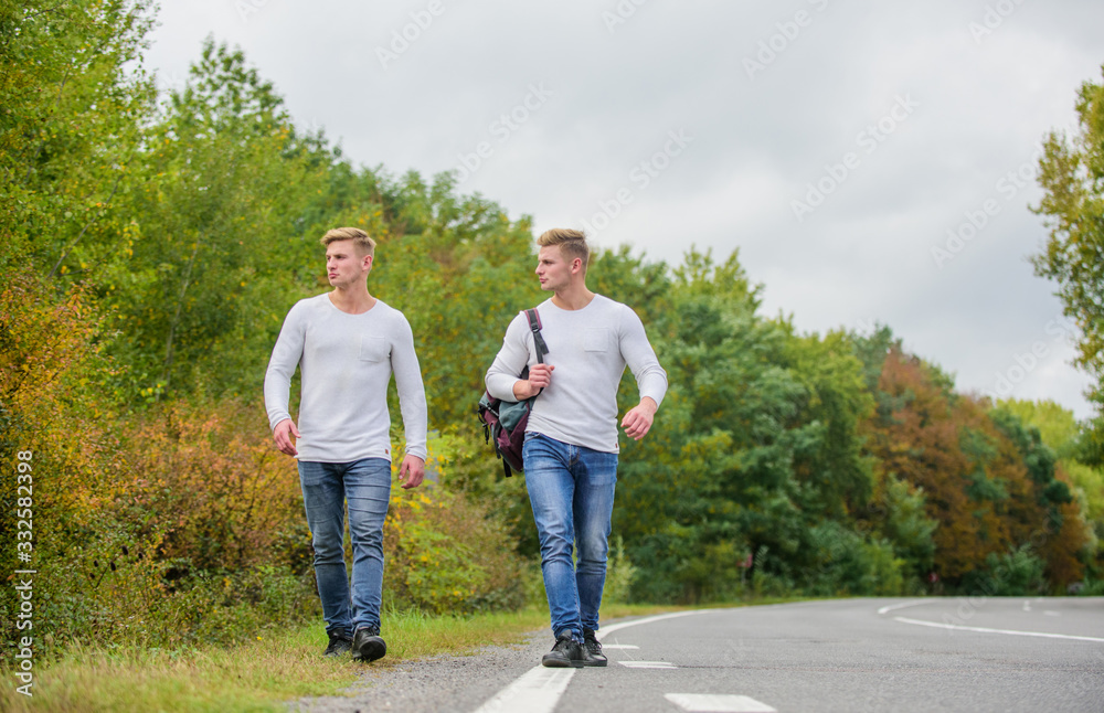 Transporting issues. Men backpack walking road. Twins walk along road. Brothers friends nature background. Long way. Adventure concept. Guys hitchhiking on road. Tourist traveler travel auto stop Transporting issues. Men backpack walking road. Twins walk along road. Brothers friends nature background. Long way. Adventure concept. Guys hitchhiking on road. Tourist traveler travel auto stop
