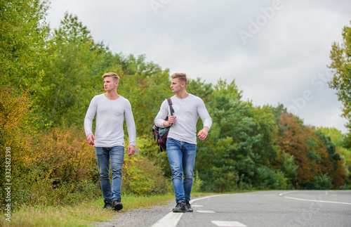 Transporting issues. Men backpack walking road. Twins walk along road. Brothers friends nature background. Long way. Adventure concept. Guys hitchhiking on road. Tourist traveler travel auto stop