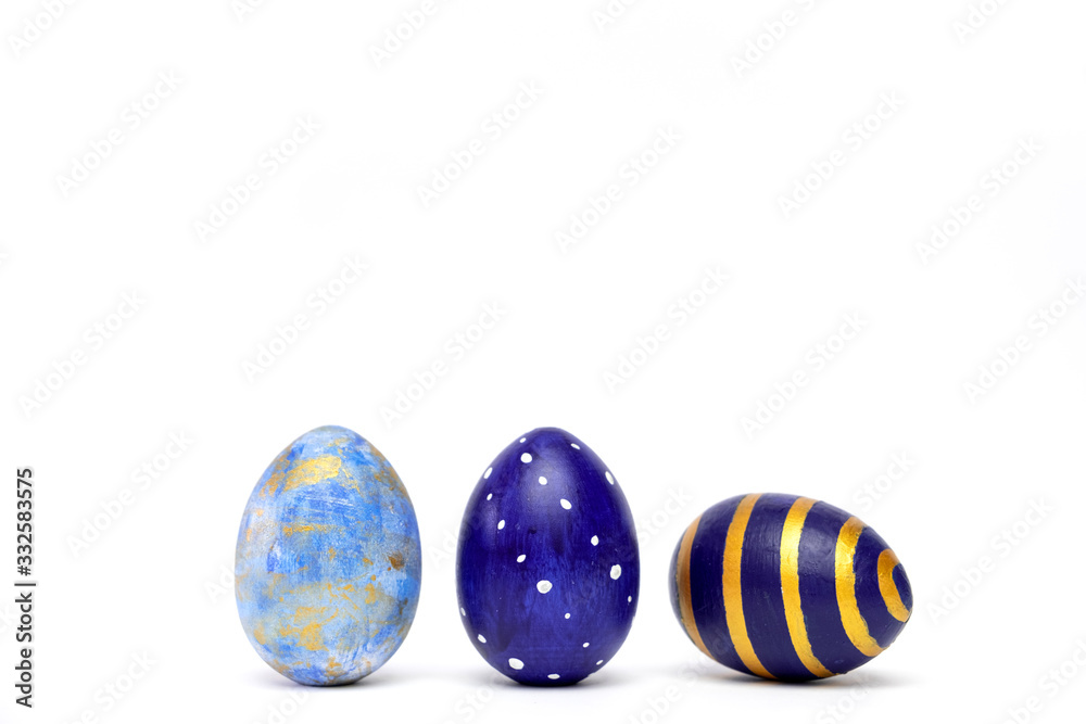 Three easter eggs trendy colored classic blue, white and golden decorated on white table. Happy Easter card with copy space for text. Minimal style. Three easter eggs trendy colored classic blue, white and golden decorated on white table. Happy Easter card with copy space for text. Minimal style.