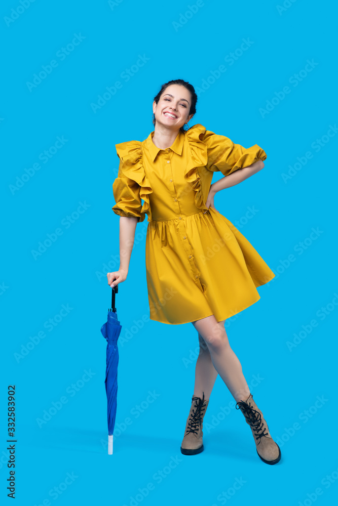 Woman in a mustard dress standing and holding an umbrella