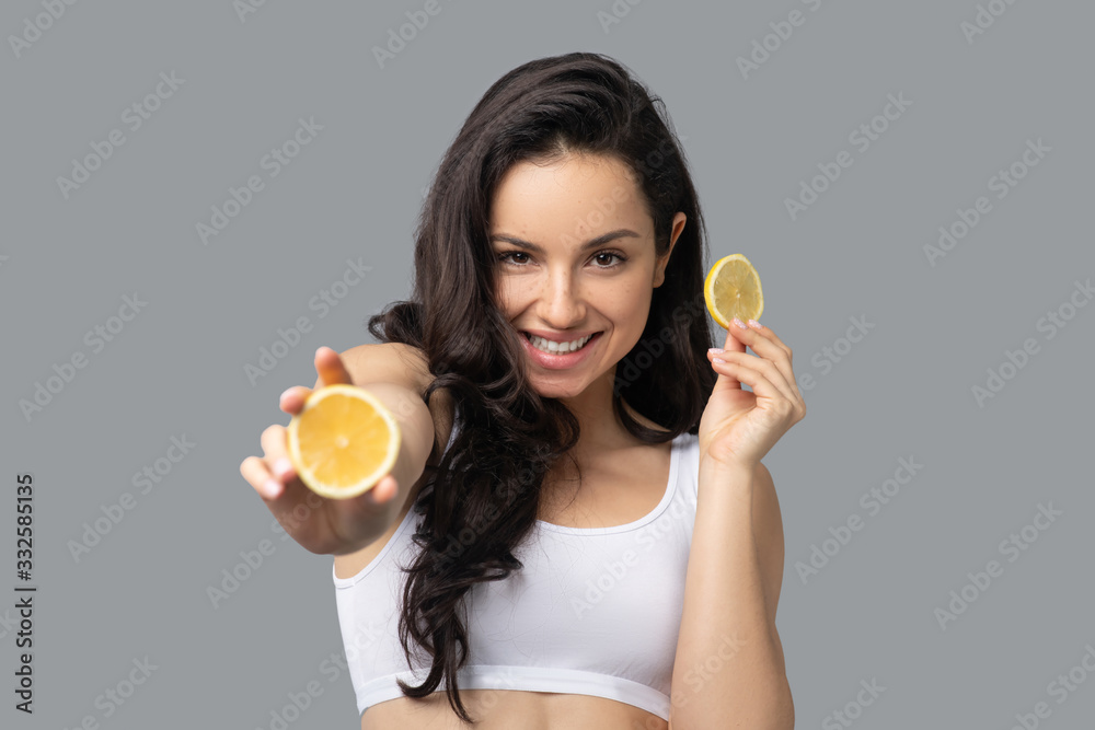 Beautiful dark-haired girl showing an orange and smiling