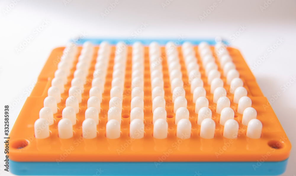 Naklejka premium White pill capsules are on hole of orange filling machines in hand