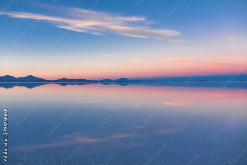 Sunrise on Salar de Uyuni in Bolivia covered with water, salt flat desert and sky reflections